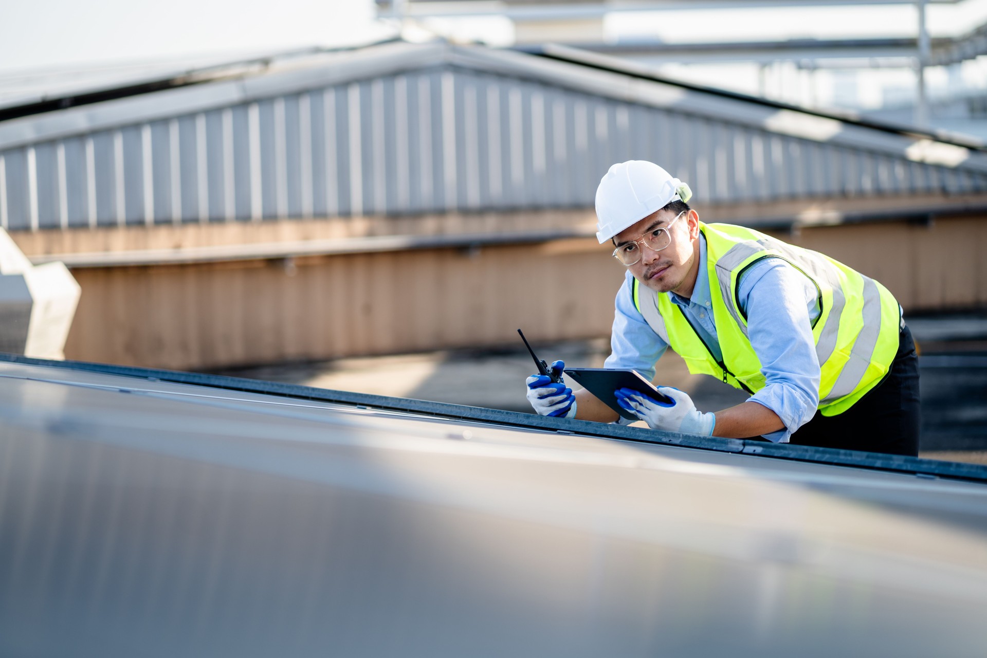 Engineer electrician using a digital tablet to check solar panels on the roof, clean energy power nature, photovoltaic systems, the energy produced by the sun, sustainable business concept.