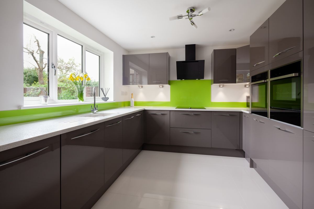 Contemporary fitted kitchen in striking lime green, grey and white colour scheme with built in appliances, white granite counter tops dual ovens and hob